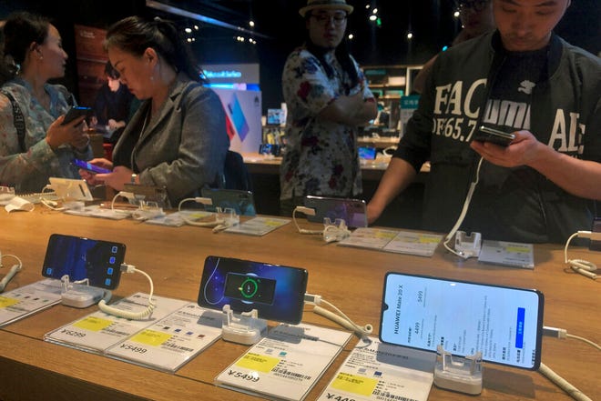 People try out Huawei smartphone models on display at an electronic store in Beijing, Monday, May 20, 2019. Google assured users of Huawei smartphones on Monday the American company's basic services will work on them following U.S. government curbs on doing business with the Chinese tech giant.