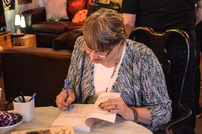 Author Cindy Kolbe signs a copy of “Struggling with Serendipity” during a book talk and signing at Mutach’s Wine Room in Marblehead. The book has local connections to Green Springs, Clyde, Toledo, and Tiffin.