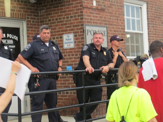 Police stand outside Dover police headquarters as about 50 protesters march by Sunday following the release of a video that shows a Dover officer punching a man in the face while he appeared to be resisting arrest early that morning, but was immobilized by other officers. May 19, 2019