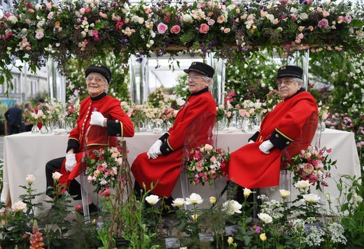 epa07586929 Chelsea pensioners sit on a floral display during the press day for the RHS Chelsea Flower Show in London, Britain, 20 May 2019. The RHS Chelsea Flower Show is a garden show held for five days by the Royal Horticultural Society in the grounds of the Royal Hospital Chelsea. It has been held since 1912 and runs this year from 21 May to 25 May. EPA-EFE/FACUNDO ARRIZABALAGA ORG XMIT: FMA0001