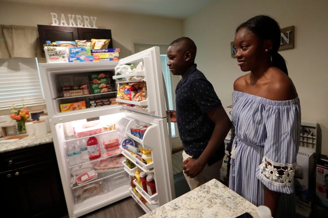 Deontae Cromartie, 13, left, and his sister Treniyah Cromartie, 14, open their fridge to find it fully stocked with food and beverages Tuesday, May 21, 2019. 