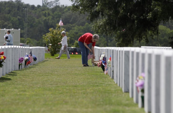 Family members place flags on the graves at Tallahassee National Cemetery Sunday in honor of Memorial Day.