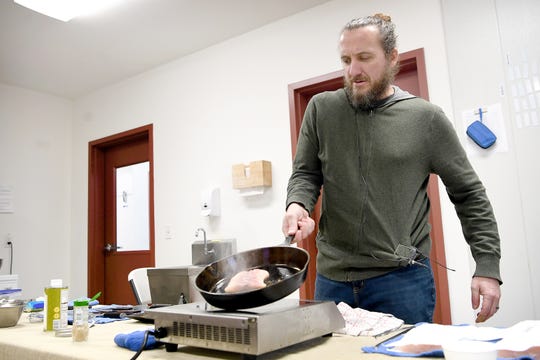 Gavin Baker works with a sturgeon filet in a pan in a makeshift kitchen he brought with him to Marshallberg Farm as he takes a tour of the facility on March 7, 2019. "One of the things I want to do with this menu is bring some things to the kitchen and to the market that aren't currently represented," he said about the new Noble Cider restaurant, The Greenhouse. 