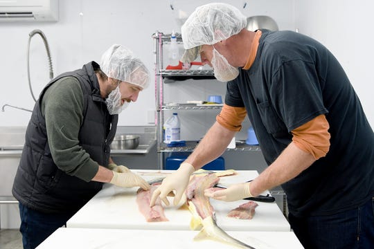 Gavin Baker looks at the meat from a sturgeon as Chris Day gives him a demonstration on butchering the fish at Marshallberg Farm as he takes a tour of the facility on March 7, 2019. 