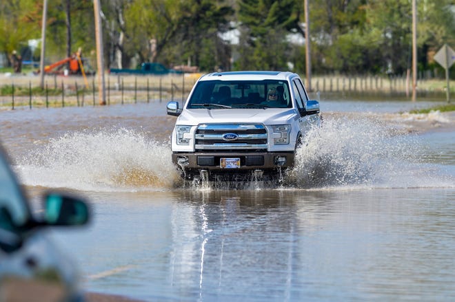 Motorist navigate flood water running over Highway 200 in the town of Sun River, Tuesday. Additional flooding was forecast by the National Weather Service in Great Falls in the Sun River area and waters are expected to remain above flood stage through next Tuesday.