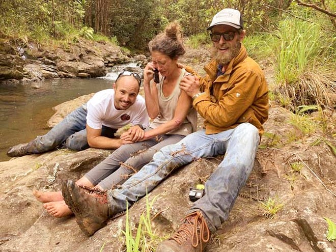 In this Friday, May 24, 2019, photo provided by Troy Jeffrey Helmer, shows Amanda Eller, second from left, after being found by searchers, Javier Cantellops, far left, and Chris Berquist, right, above the Kailua reservoir in East Maui, Hawaii, on Friday afternoon. The men spotted Eller from a helicopter and went down to retrieve her.