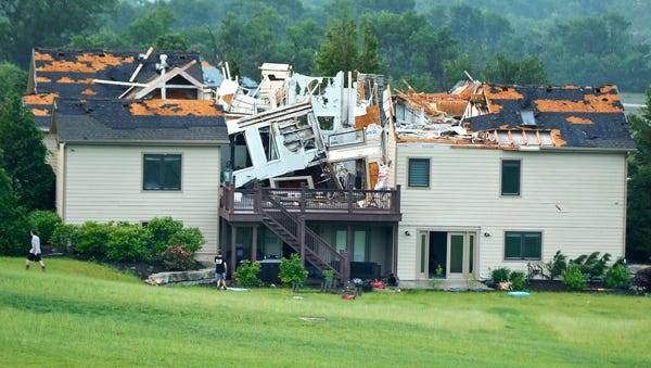 A destroyed home sits in a neighborhood after it...