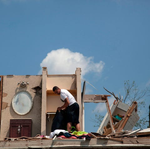 A man gathers his belongings from his damaged...