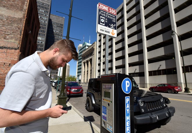 Gjon July, 25, pays for parking on his Park Detroit cellphone app on Lafayette near Shelby on May, 30, 2019.