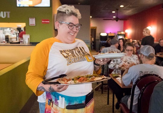 Shelby Phelps delivers food to a table with a smile at Spankey's Una Pizza on Evansville's West Side Friday, May 10, 2019. Phelps is a full-time English and journalism teacher at Central High School and works at the restaurant on the weekends. 