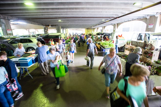People stroll between booths during the Farmers Market, Wednesday, May 29, 2019, below the Chauncey Swan Parking Ramp, between Burlington and Washington Streets in Iowa City, Iowa.