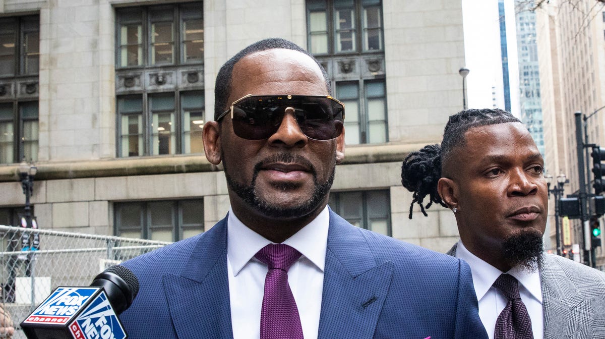 FILE - This March 13, 2019 file photo shows R. Kelly and his publicist Darryll Johnson, right, leaving The Daley Center after an appearance in court for Kelly's child support case in Chicago. Prosecutors in Chicago have charged Kelly with 11 new sex assault charges, some that are more serious than those first filed against him in February. The Chicago Sun-Times reported Thursday, May 30, on its website that the charges include counts that carry a potential sentence of   up to 30 years in prison. The charges say the alleged offenses happened in 2010. (Ashlee Rezin/Chicago Sun-Times via AP, File) ORG XMIT: ILCHS306