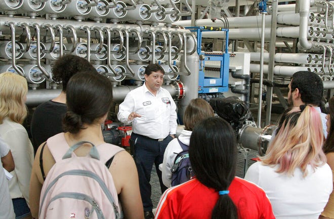 In this May 2, 2019, photo, college students listen as El Paso Water worker Hector Sepulveda explains the desalination process at a plant in El Paso, Texas. The silver pipes push water through tightly packed membranes inside the white pipes, drawing minerals out of the brine. As the planet warms and weather patterns turn more extreme, droughts - as well as floods - in the state generally have worsened. El Paso, which has about 700,000 people living in a desert region that gets only 9 inches (23 centimeters) of rain annually, receives international groups wanting to learn more about innovative facilities like the largest inland desalination plant in the United States.