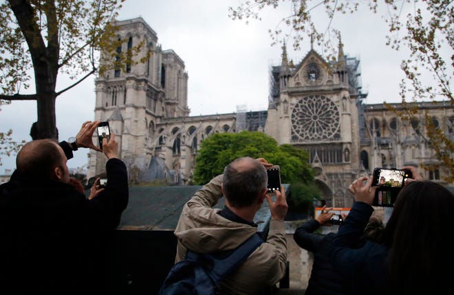 People take photos of the Notre Dame Cathedral in Paris in April, one day after a major blaze broke out at Paris' iconic cathedral. Children under 7 and pregnant women who live near Notre Dame Cathedral may have been exposed to lead pollution in the area.
