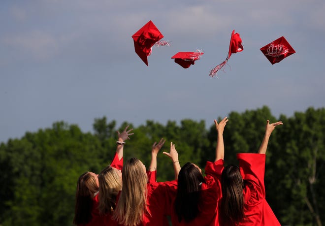 Students toss their caps into the air while taking pictures prior to the Kimberly High School commencement ceremony Wednesday in Kimberly. Post-graduation celebrations have become a traditional across Wisconsin.