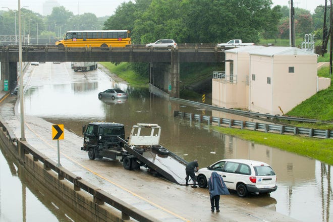 A towing service prepares to hauls out a U.S. Postal Service van from the I-110 southbound curves near the Governor's Mansion, as a result of flash flooding from heavy rains.