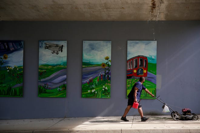 A man pauses as he walks past four of the eight panels on the new 18th st. underpass mural installation painted by the Mayor's Youth Council, Friday, June 7, 2019, in Lafayette.