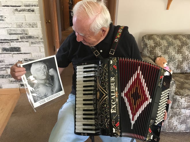 Glenn L. Schmidt holds the signed photo and one of his accordions. He got the photo signed after playing the Beer Barrel Polka for Da Crusher.
