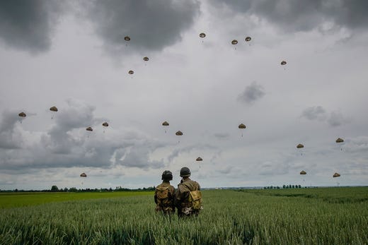 Military re-enactors look on as 280 paratroopers take part in a parachute drop onto fields on June 5, 2019 at Sannerville, France. Veterans, families, visitors and military personnel are gathering in Normandy on June 6th to commemorate the 75th anniversary of the Normandy Landings which heralded the Allied advance towards Germany and victory in Europe 11 months later.