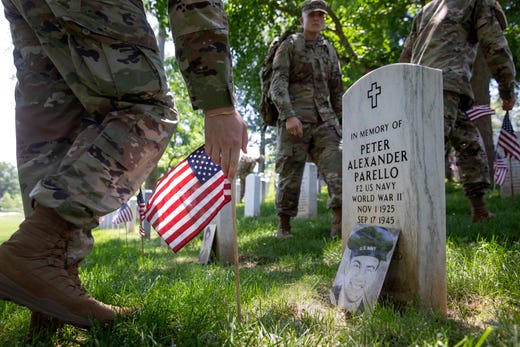 Soldiers with the Third U.S. Infantry Regiment (The Old Guard), place small U.S. flags at headstones during the 'Flags-In' ceremony for Memorial Day weekend at Arlington National Cemetery in Arlington, Va. on May 23, 2019. About 1,000 Old Guard Soldiers placed more than 250 thousand flags at the base of headstones and other locations of the cemetery. 