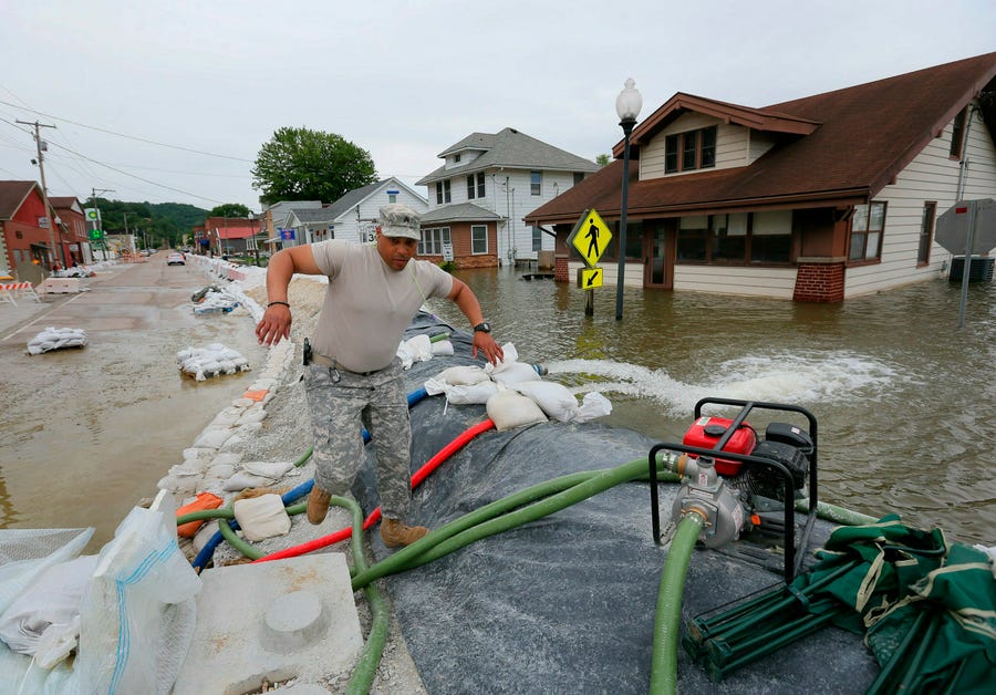 Illinois National Guard Sgt. Joey White climbs the temporary flood wall built on Main Street in Grafton, Ill., Saturday, June 8, 2019.