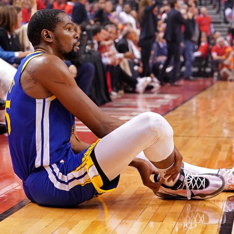 Kevin Durant sits on the court after suffering an...