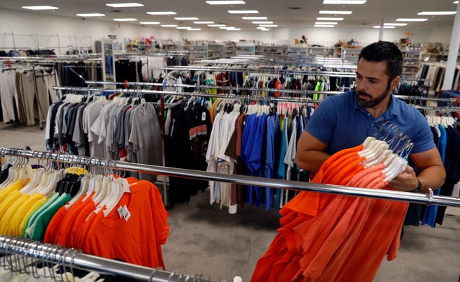 Ohio Thrift employee Kevin Tehranchi organizes T-shirts on racks Wednesday afternoon, June 12, 2019, at the new store in Lancaster.