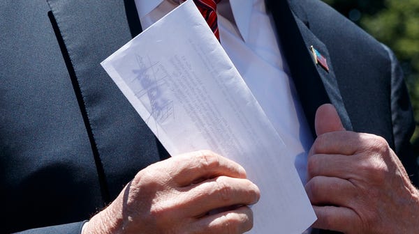 President Donald Trump holds a letter as he...