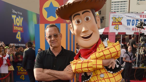 Tom Hanks, left, poses with his character Woody...