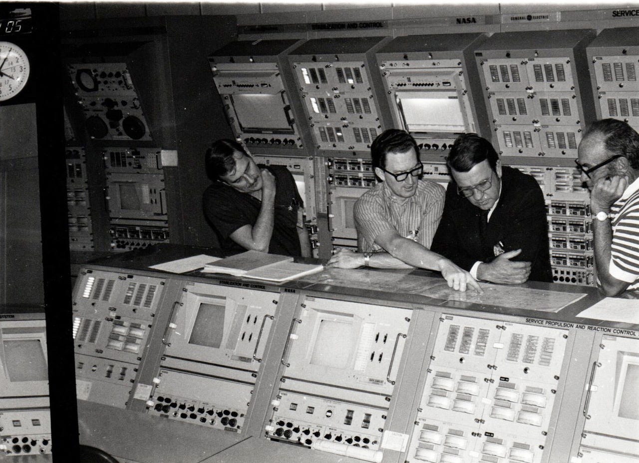 Propulsion engineer John Tribe, pointing, looking over plans during the early 1960s.