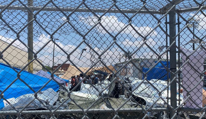 In this June 1, 2019, photo, provided by New Mexico State University professor Neal Rosendorf, migrants are seen through fencing inside a temporary outdoor encampment where they're waiting to be processed in El Paso, Texas.