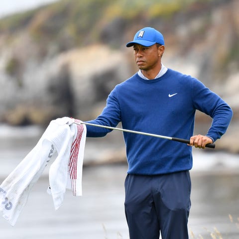 Tiger Woods wipes down a club on the 18th hole...