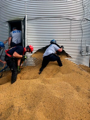 In this May 30, 2019 photo provided by the Ross Township Fire Department rescue personnel shovel soybeans out of the bottom of a bin during an effort to rescue farmer Jay Butterfield, who was buried up to his neck inside. He became buried up to his neck while trying to break up clumps of soybeans in the bin on his farm in Ross Township, Ohio.