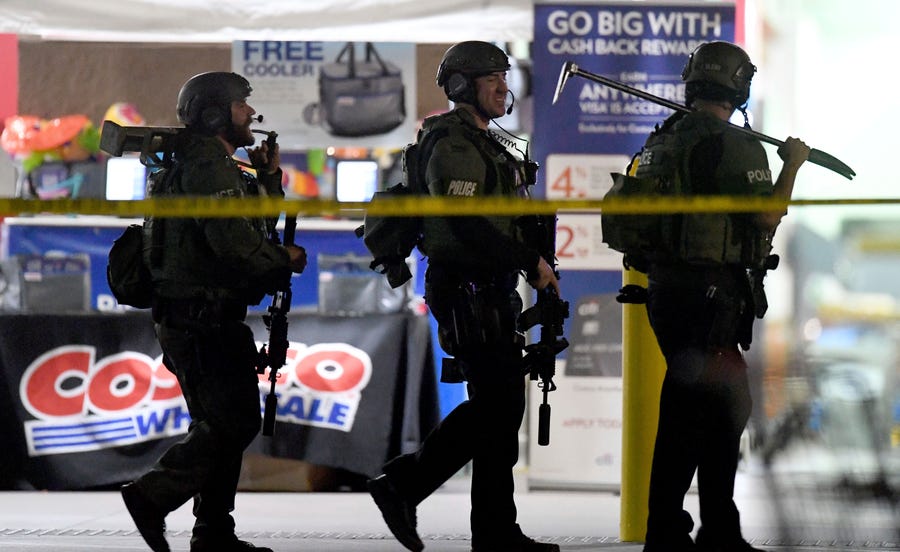 Police officers exit the Costco following a shooting inside the wholesale warehouse in Corona, Calif.,  Friday.  A gunman opened fire inside the store during an argument,  killing a man, wounding two other people and sparking a stampede of terrified shoppers before he was taken into custody, police said. The man involved in the argument was killed and two other people were wounded, Corona police Lt. Jeff Edwards said.  (Will Lester/Inland Valley Daily Bulletin/SCNG via AP) ORG XMIT: CAANR101