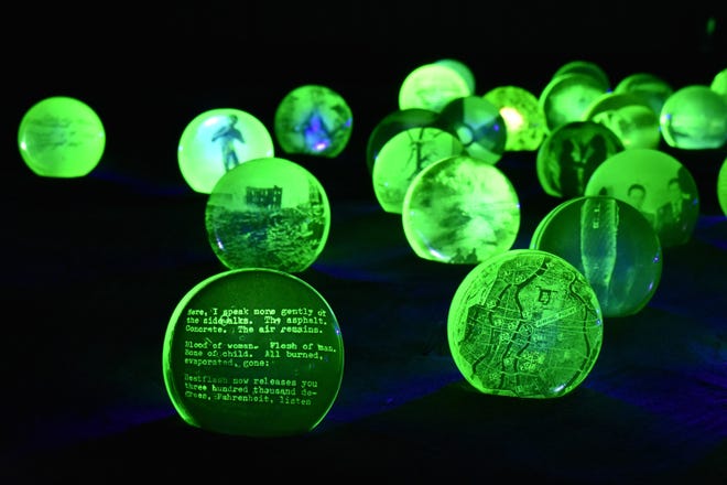 This is a detail of Jo Yarrington's installation 'Uranium Game,' created with uranium glass, photo decals, blacklight, aluminum oxide, grout, and featuring an audio player playing a poem by Allen Ginsburg.  It is part of 
WheatonArts: Emanation 2019.'