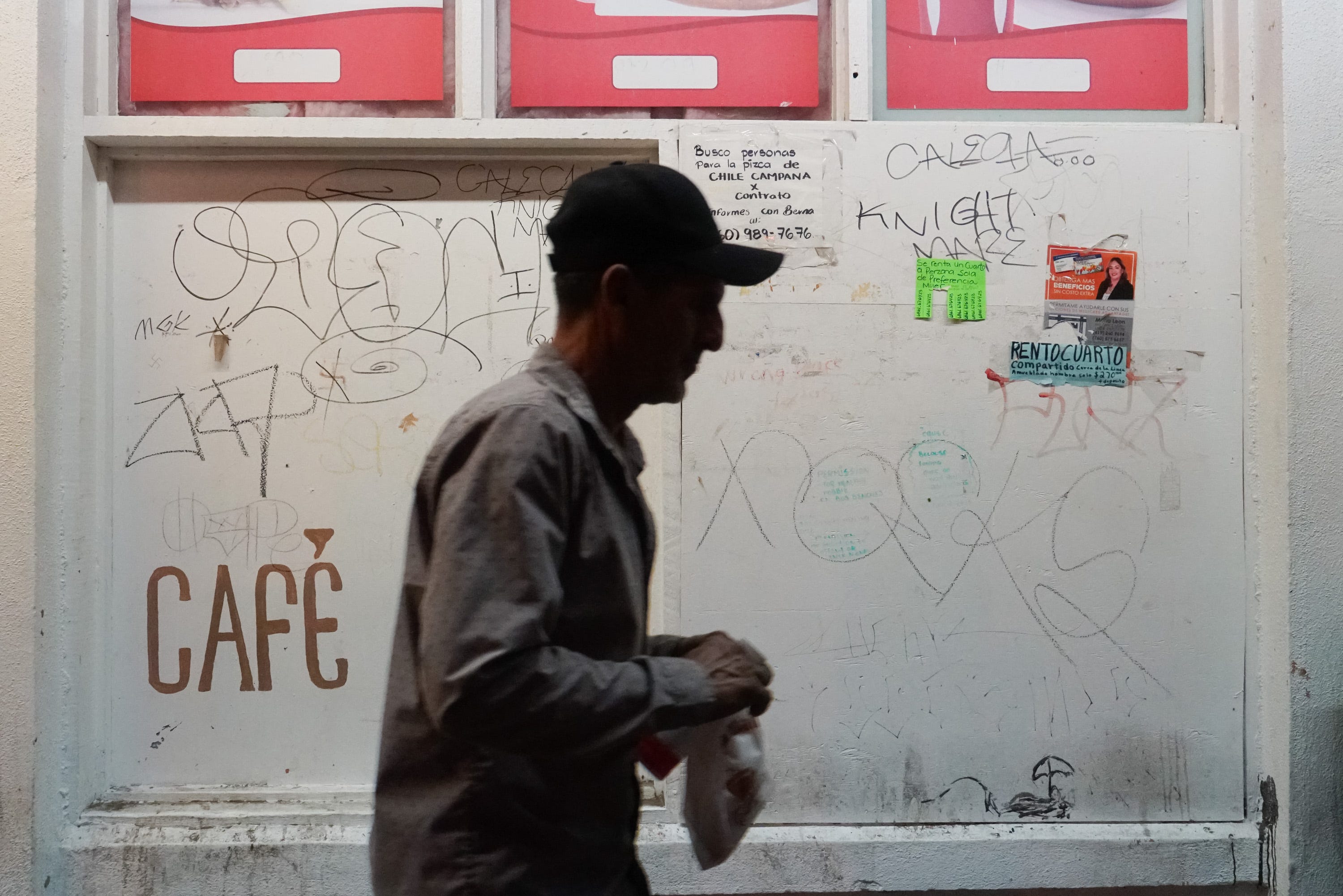 While farmworkers wait for work outside of Donut Avenue, a man walks by with a bag from the store, Calexico, Calif., 1:37 AM, June 12, 2019.