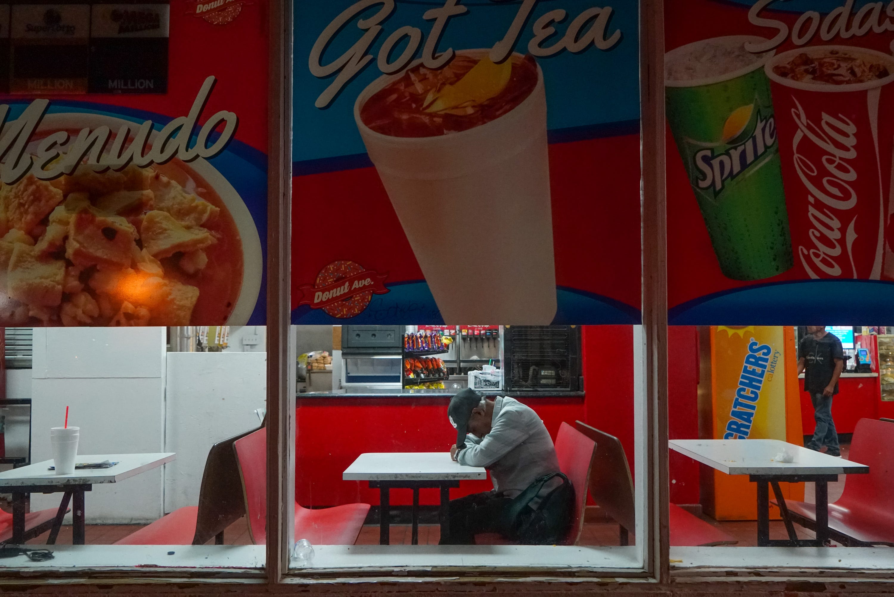 A man sleeps on a table at Donut Avenue, Calexico, Calif., 12:04 AM, June 12, 2019.