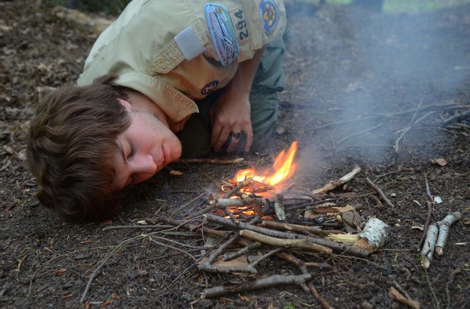 Eagle Scout Ian Boden blows softly to fan a small fire as he builds a campfire at Silver Trails Boy Scout Camp in Jeddo in 2013.