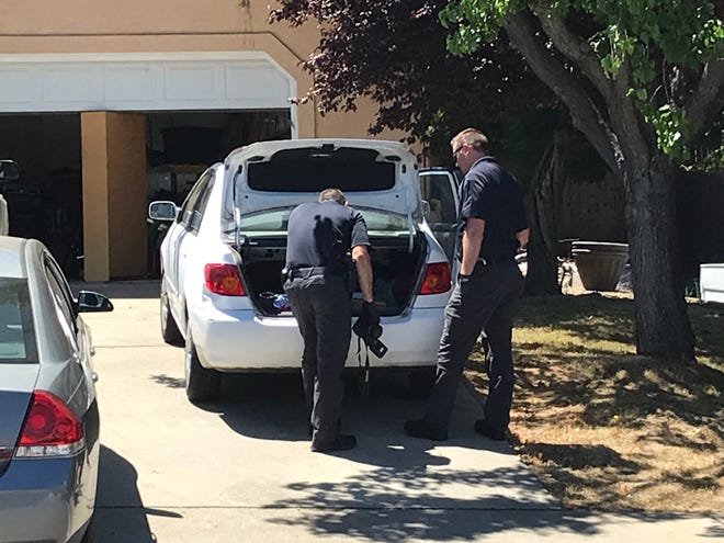 Redding police inspect the trunk of a car parked at a home in the 1700 block of Galway Drive.
