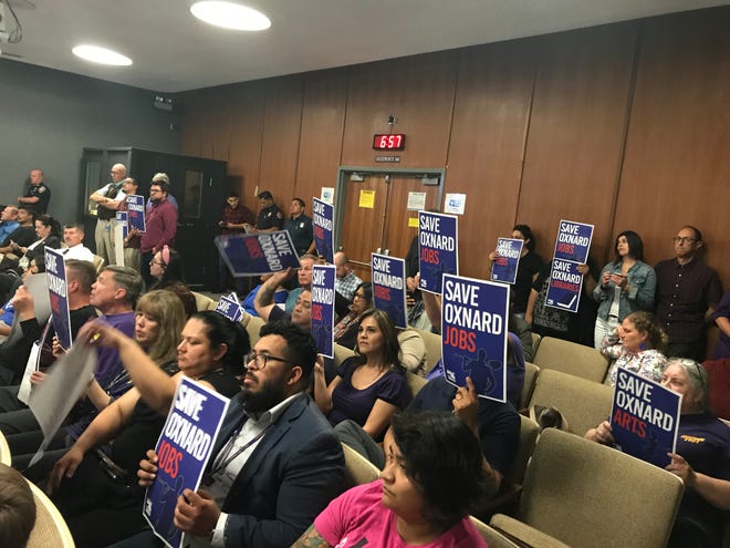 People in the audience at Tuesday's Oxnard City Council meeting hold up signs calling on Oxnard leaders to save some of the proposed budget cuts.  Council adopted a budget on a 6-to-1 vote.