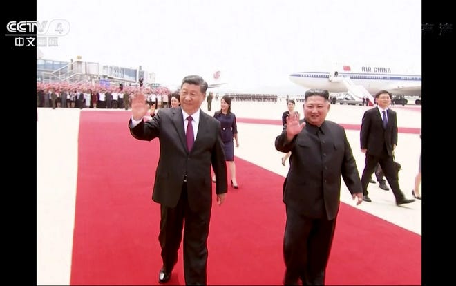 In this image taken from a video footage run by China's CCTV, Chinese President Xi Jinping, left, and North Korean leader Kim Jong Un wave as President Xi arrived at an airport in Pyongyang, North Korea, Thursday, June 20, 2019.