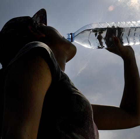 A woman drinks water from a plastic bottle on...