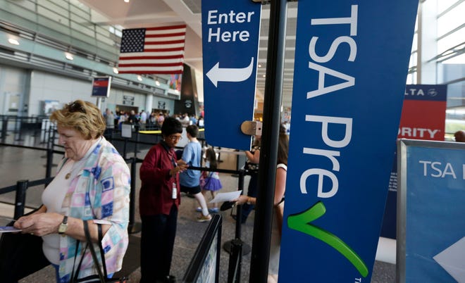 Travelers pass a sign for the Transportation Security Administration's Precheck line as they walk to their departure gate in Terminal A at Logan International Airport on June 27, 2016, in Boston.