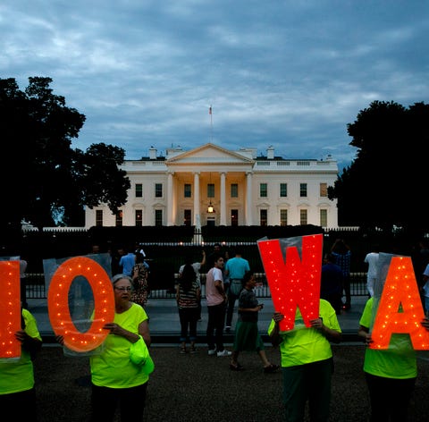 Protesters hold signs spelling out, "No War,"...