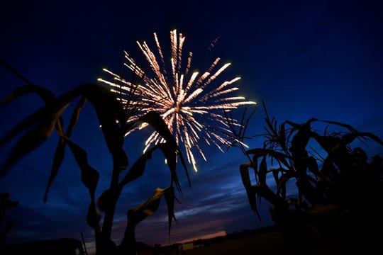 Corn stalks are silhouetted by the evening sky as a firework explodes overhead Saturday during Boombah. The fireworks show was the 25th year the Smith family said they have held it, charging no admission and using fireworks available for purchase at their stand.