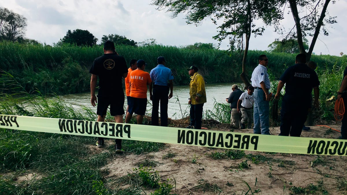 Authorities stand behind yellow warning tape along the Rio Grande bank where the bodies of Salvadoran migrant Oscar Alberto Martínez Ramírez and his nearly 2-year-old daughter, Valeria, were found in Matamoros, Mexico, on June 24, 2019. They drowned trying to cross the river to Brownsville, Texas. Martinez's wife, Tania, told Mexican authorities she watched her husband and child disappear in the strong current.