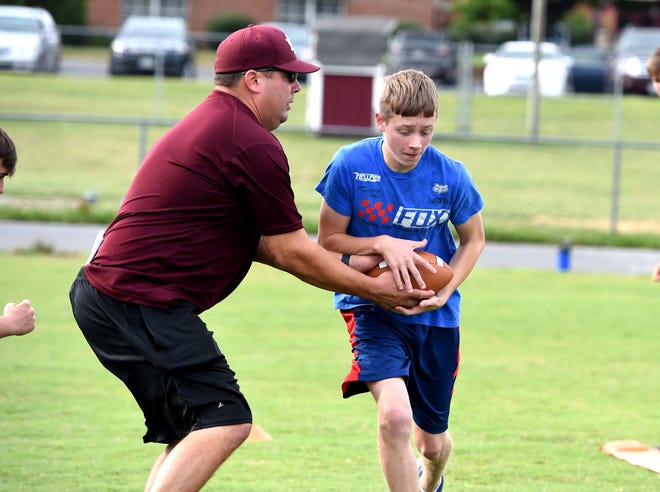 Stuarts Draft assistant coach Josh Podgorski works with the running backs at the Stuarts Draft youth football camp Tuesday night.