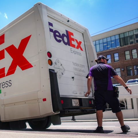 A FedEx delivery truck is loaded by an employee...