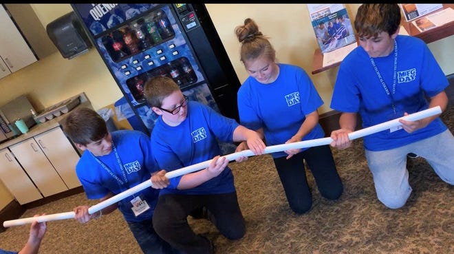 Students of the Coshocton Manufacturing and Technology Camp play a game designed to build leadership and teamwork skills. Youth must use a series of pipes to transport a marble across a room to drop into a bucket.