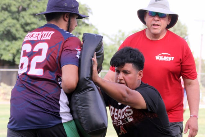 Justin Morales punches the bag during a line backer drills as coach Richard Perales looks on.